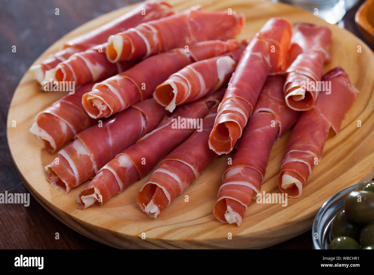 Spanish tasty meal rolls of prosciutto di parma at wooden desk, close