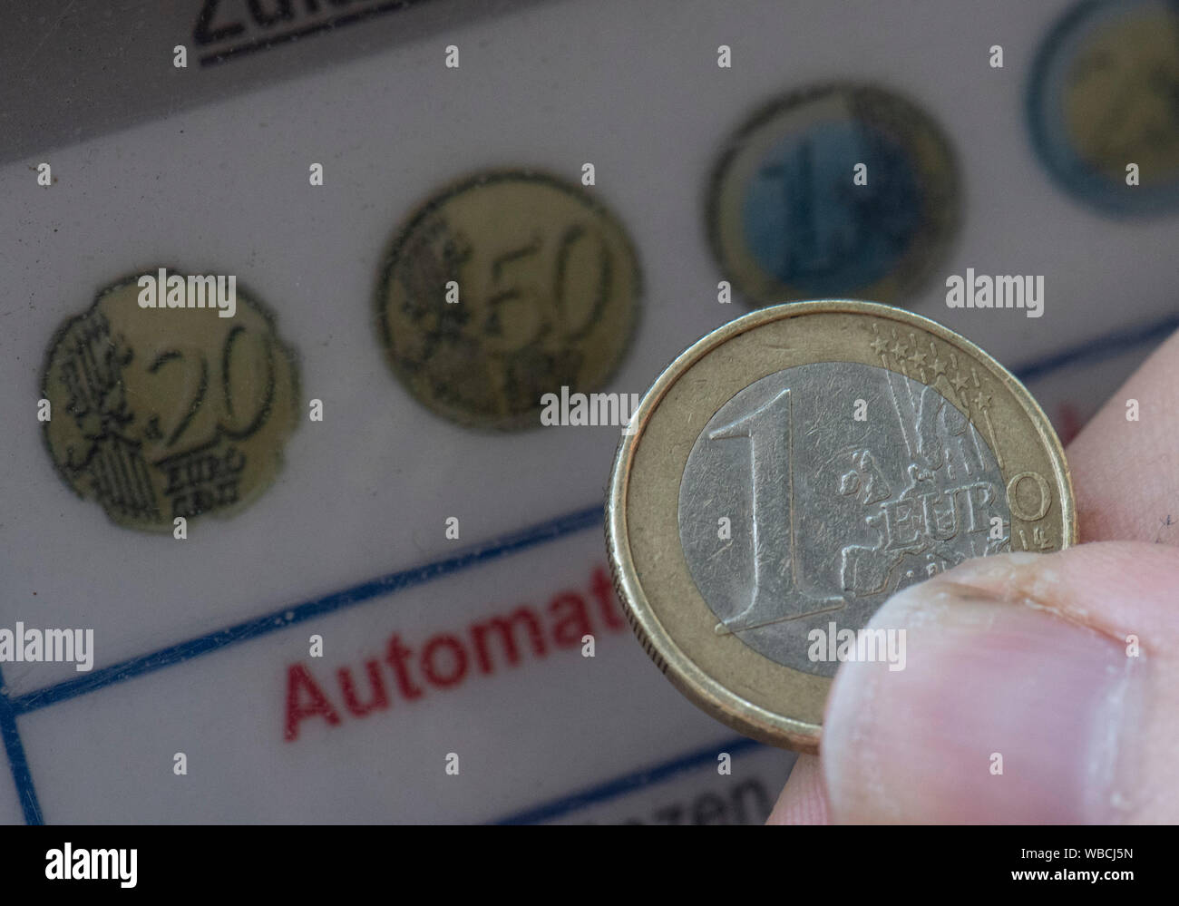 ILLUSTRATION - 26 August 2019, Hessen, Frankfurt/Main: A Euro coin is held in front of the slot of a parking machine. Against the background of an impending ban on diesel driving, parking fees in the city centre are to be raised. Photo: Boris Roessler/dpa Stock Photo