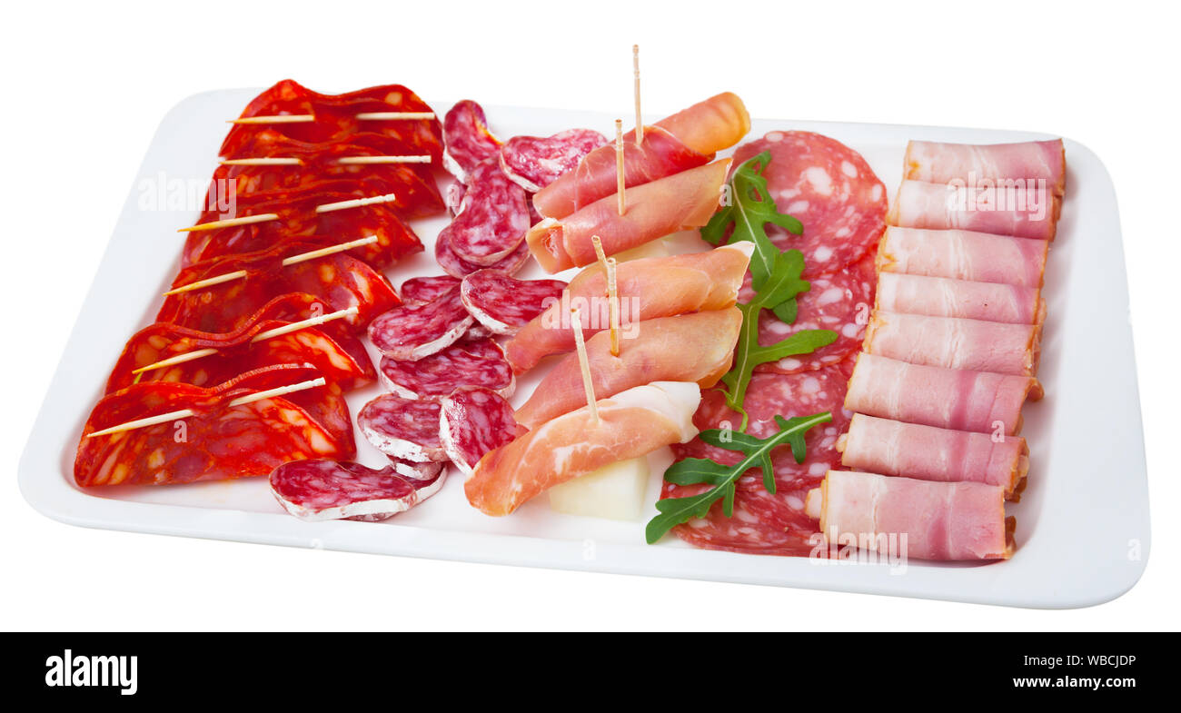 Cold smoked meat plate with traditional Spanish chorizo, fuet and salami sausages, sliced bacon and jamon. Isolated over white background Stock Photo