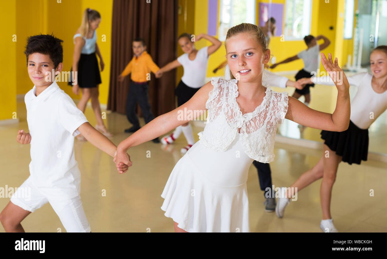 Boys and girls having dancing class with young female trainer in dance