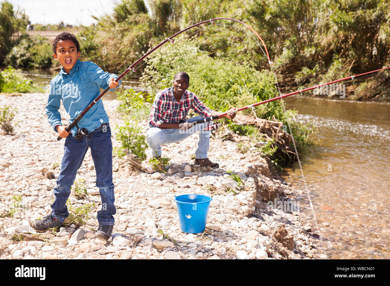 Little African boy fishing with his father and pulling fish Stock Photo