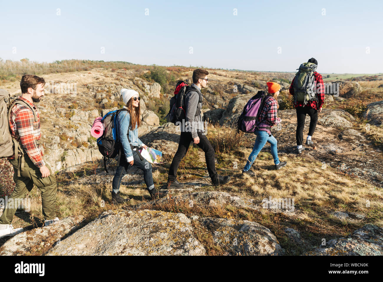 Group of young happy friends carrying backpacks on a hike together ...