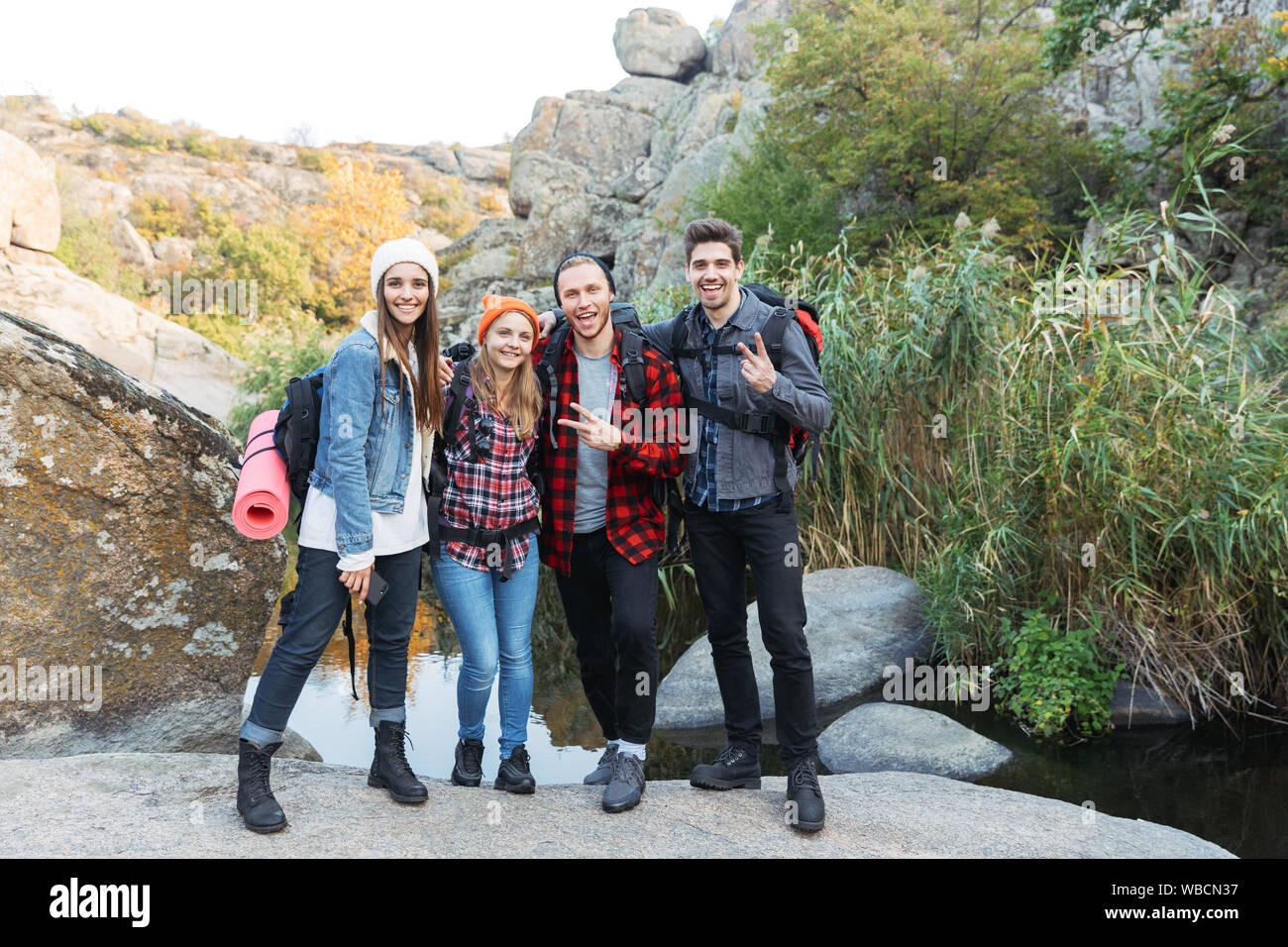 Group of young happy friends carrying backpacks on a hike together ...