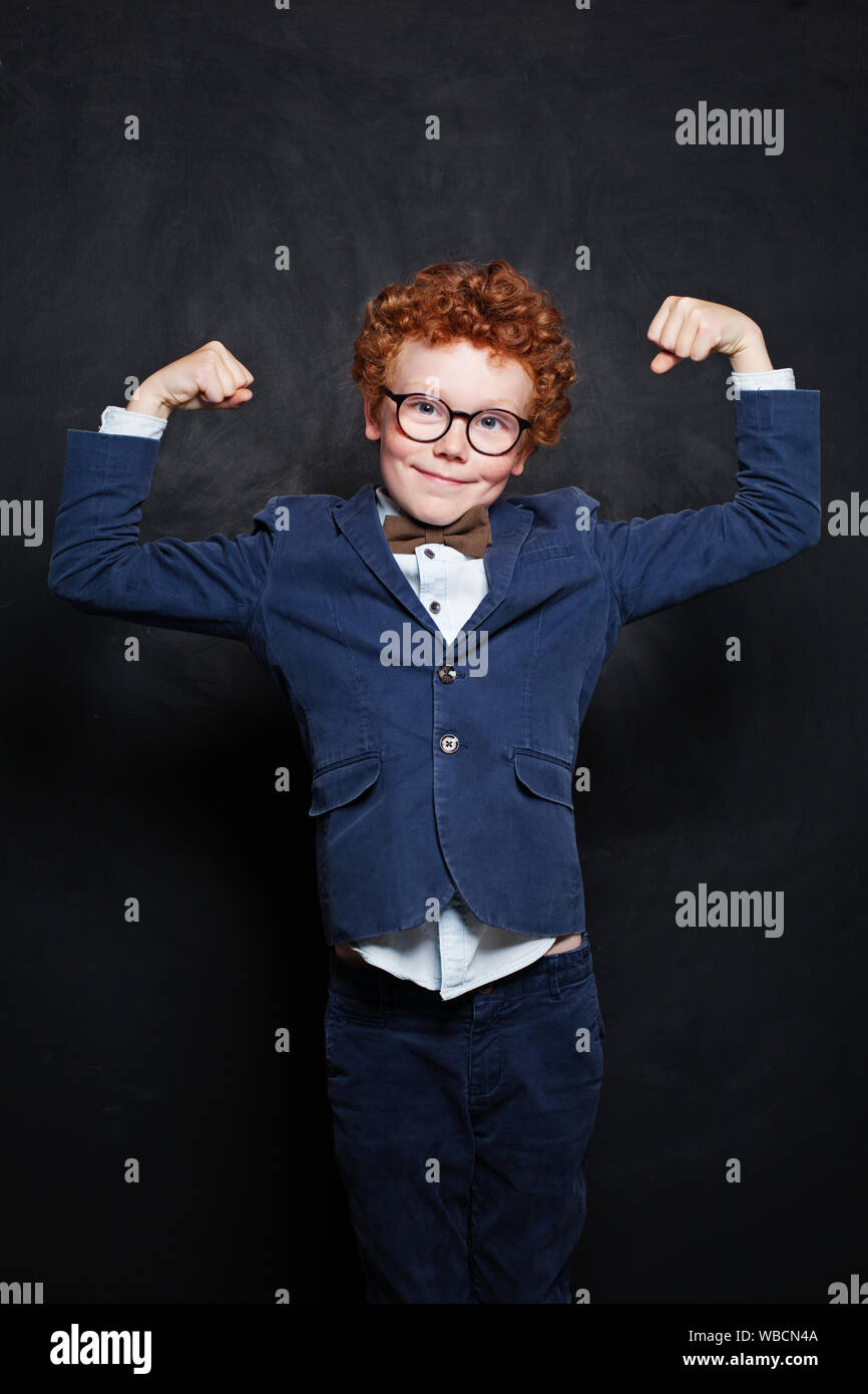 Strong little child boy on blackboard background Stock Photo - Alamy