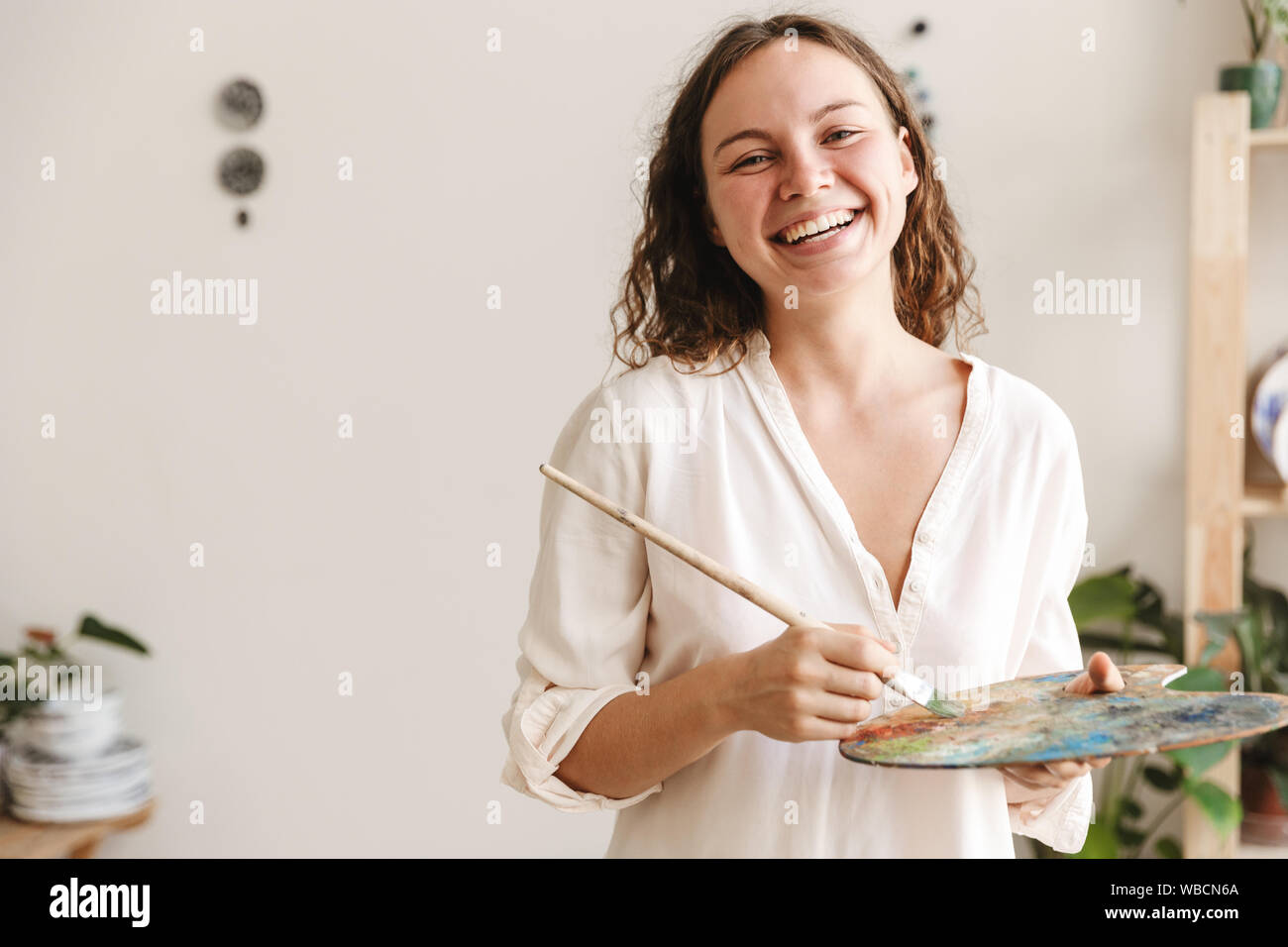 Portrait of smiling artistic woman holding color palette and paint ...