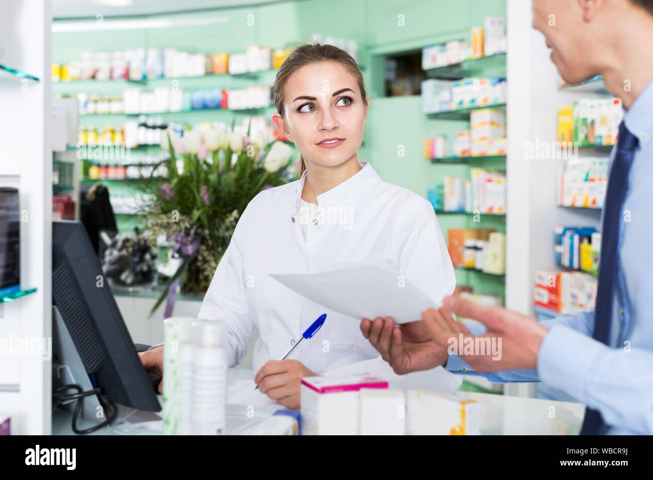 Female pharmacist is helping korean male client choose medicine near
