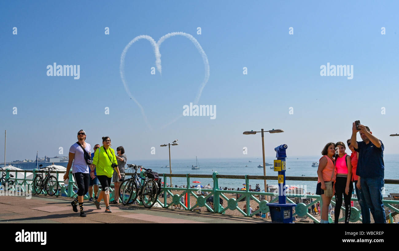 Brighton, UK. 26 August 2019.  Two pilots create a heart in the sky off Brighton beach which is packed on August Bank Holiday Monday in hot sunshine as temperatures soar into the high twenties again . Yesterday saw record temperatures being set for an August bank holiday in West London . Credit : Simon Dack / Alamy Live News Stock Photo