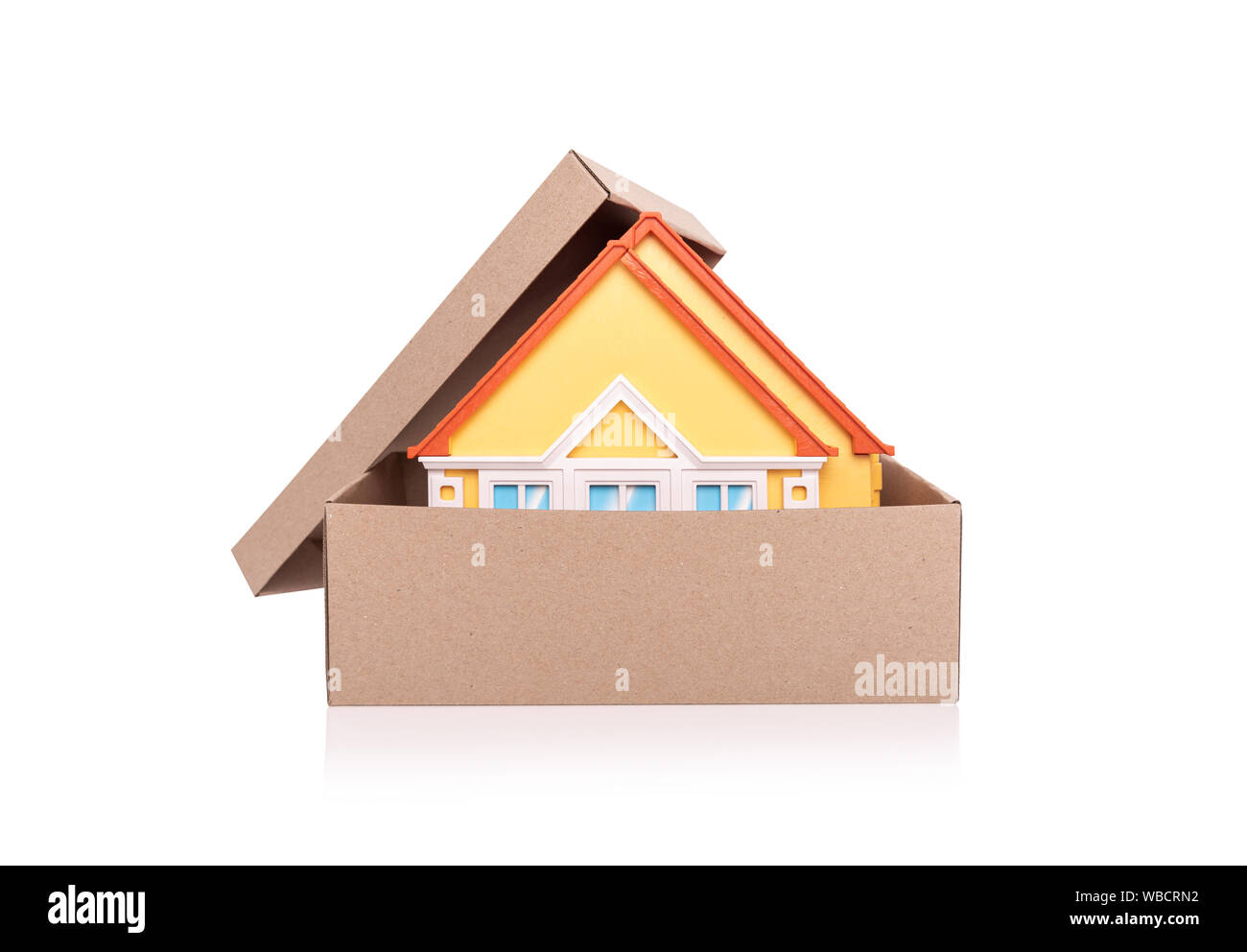 Toy model of a house in a cardboard box on white background. Stock Photo