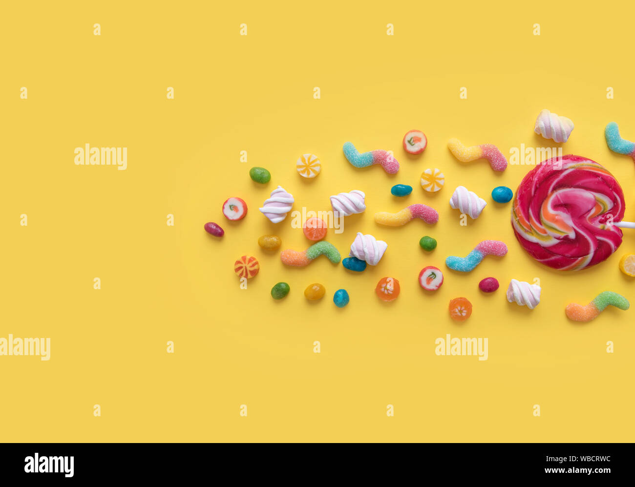 Scattering of sweets on a yellow background. Stock Photo