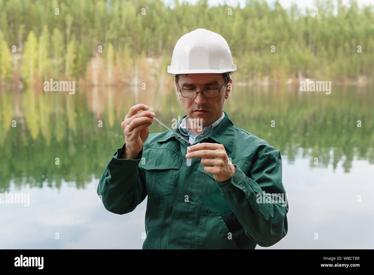 industrial ecologist or chemist takes a sample of water from lake at the site of a flooded quarry Stock Photo
