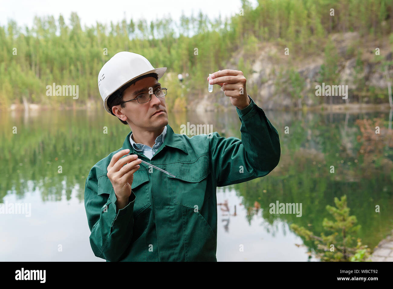 industrial ecologist or hydrologist visually evaluates the response of a water sample from lake at the site of a flooded quarry Stock Photo