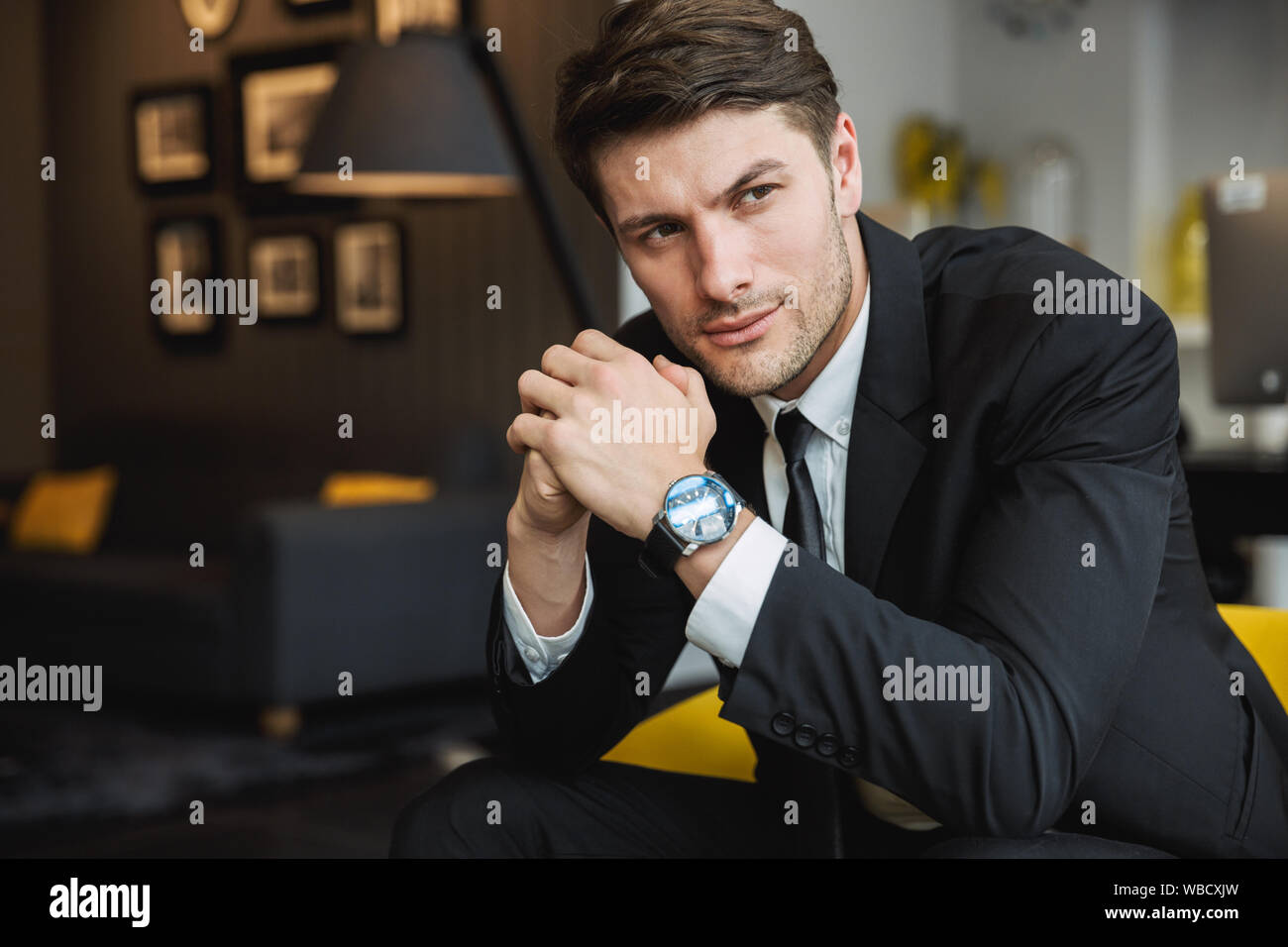 Portrait of confident young businessman wearing formal black suit and ...