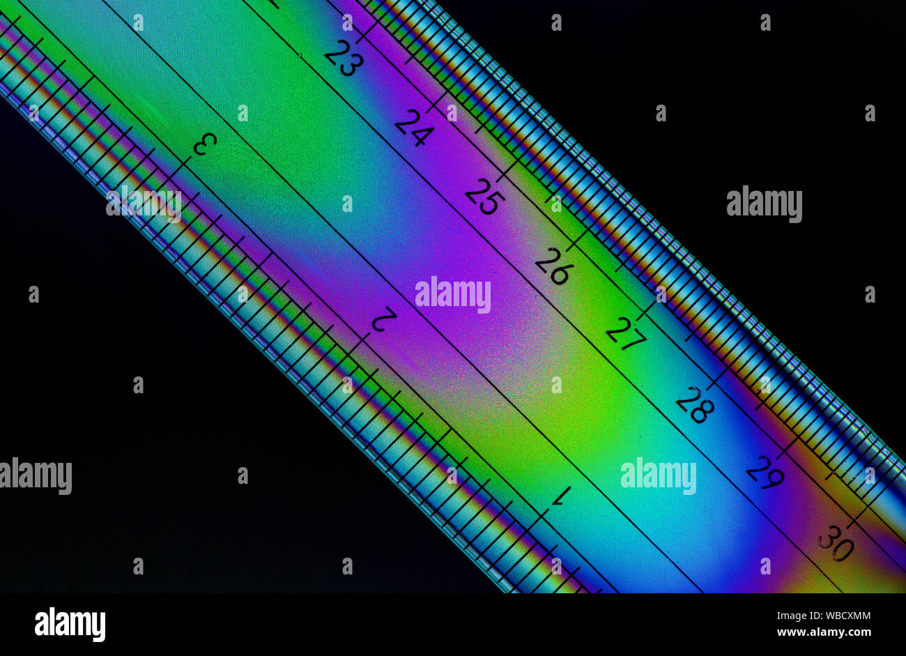 Cross polarised image of a ruler showing the colourful stress patterns in the plastic Stock Photo