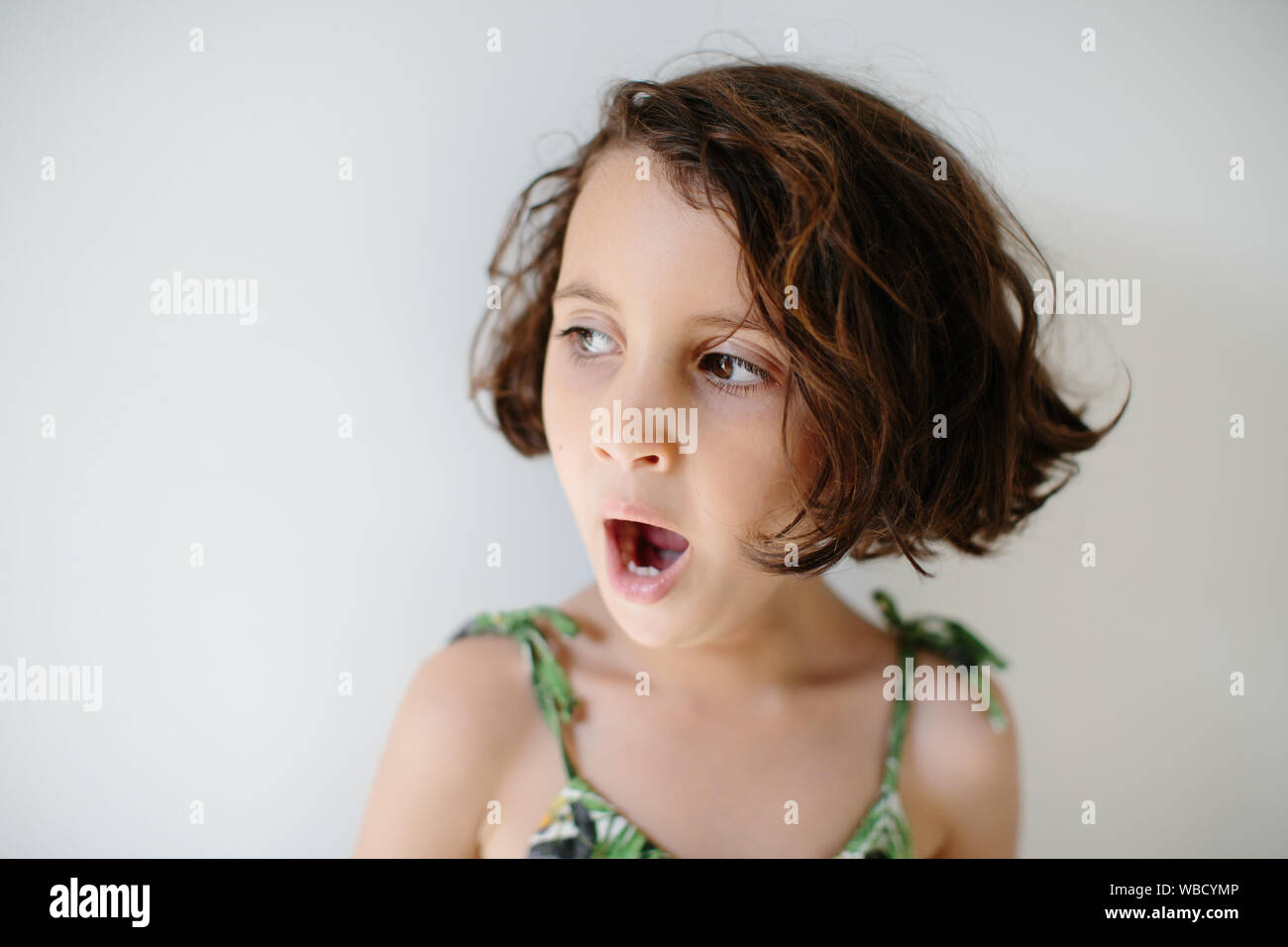 A 5 Year Old Girl Is Yawning Over White Background She Has Short Dark Hair She Wears Summer Dress Stock Photo Alamy