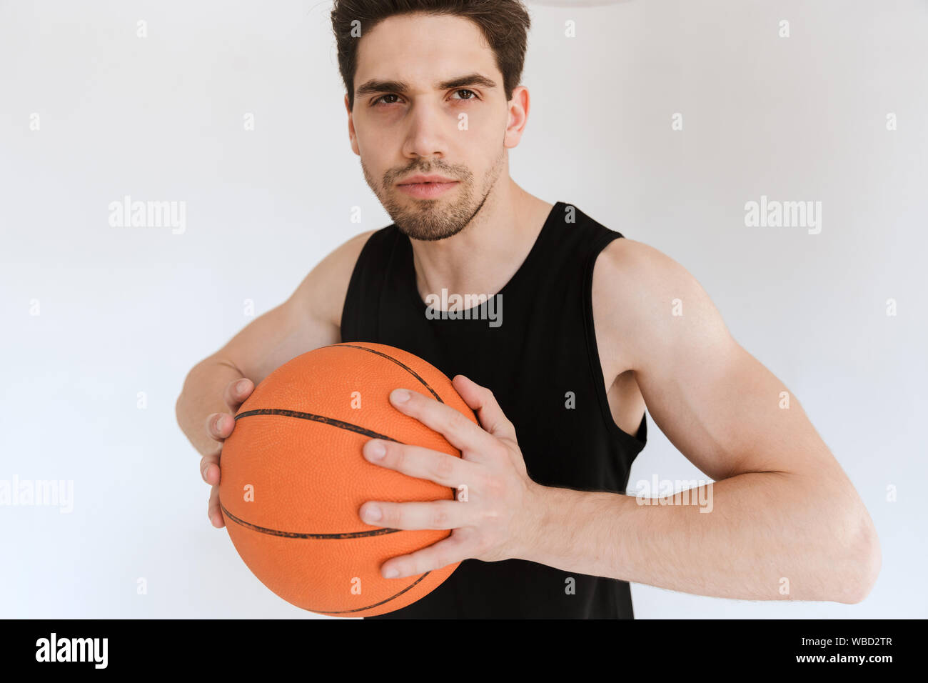 Image of a serious strong young sports man basketball player holding