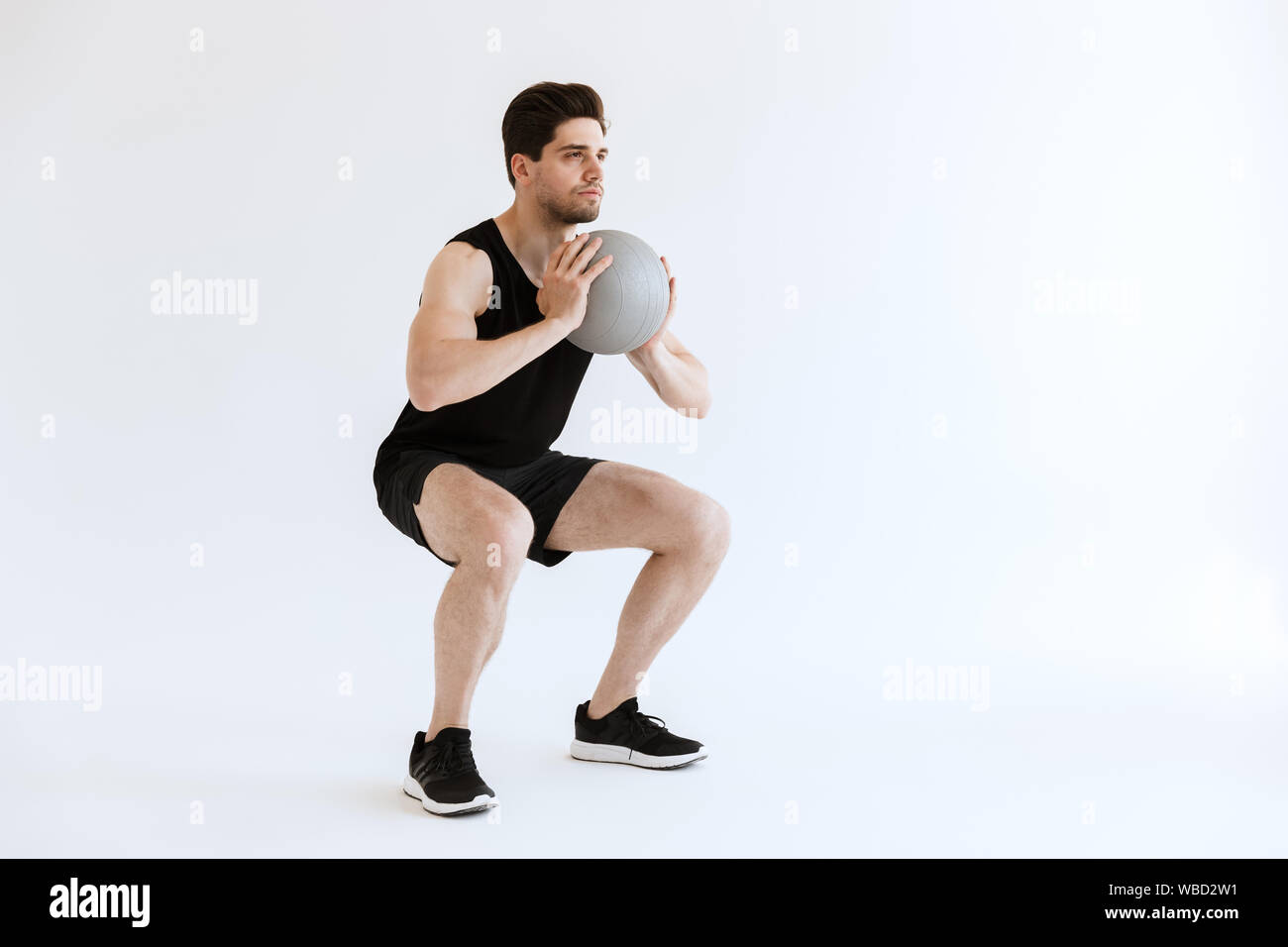 Photo of a strong young sports man make squats exercise with ball