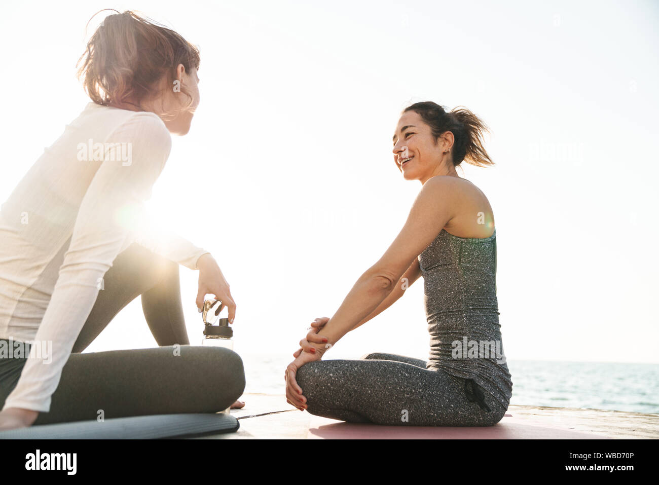 Image of young fitness women in sportive clothes smiling while sitting