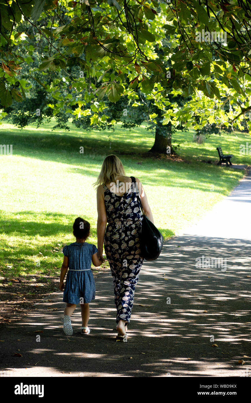mother and daughter holding hands walking through a park Stock Photo ...