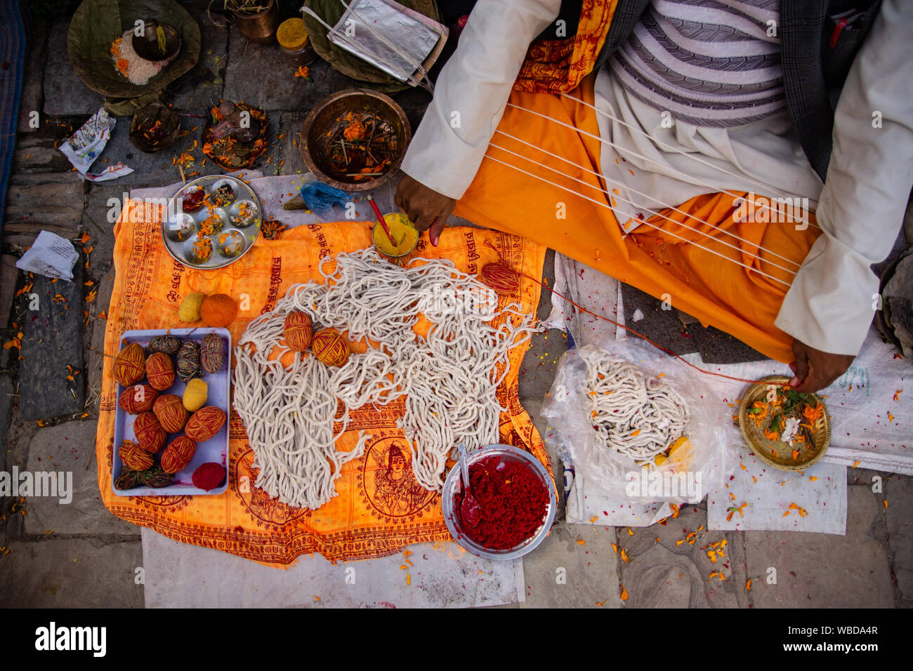 A Nepalese Hindu Brahmin Priest holds Janai or sacred thread as he waits for devotees on the occasion of the Janai Purnima Festival. Stock Photo