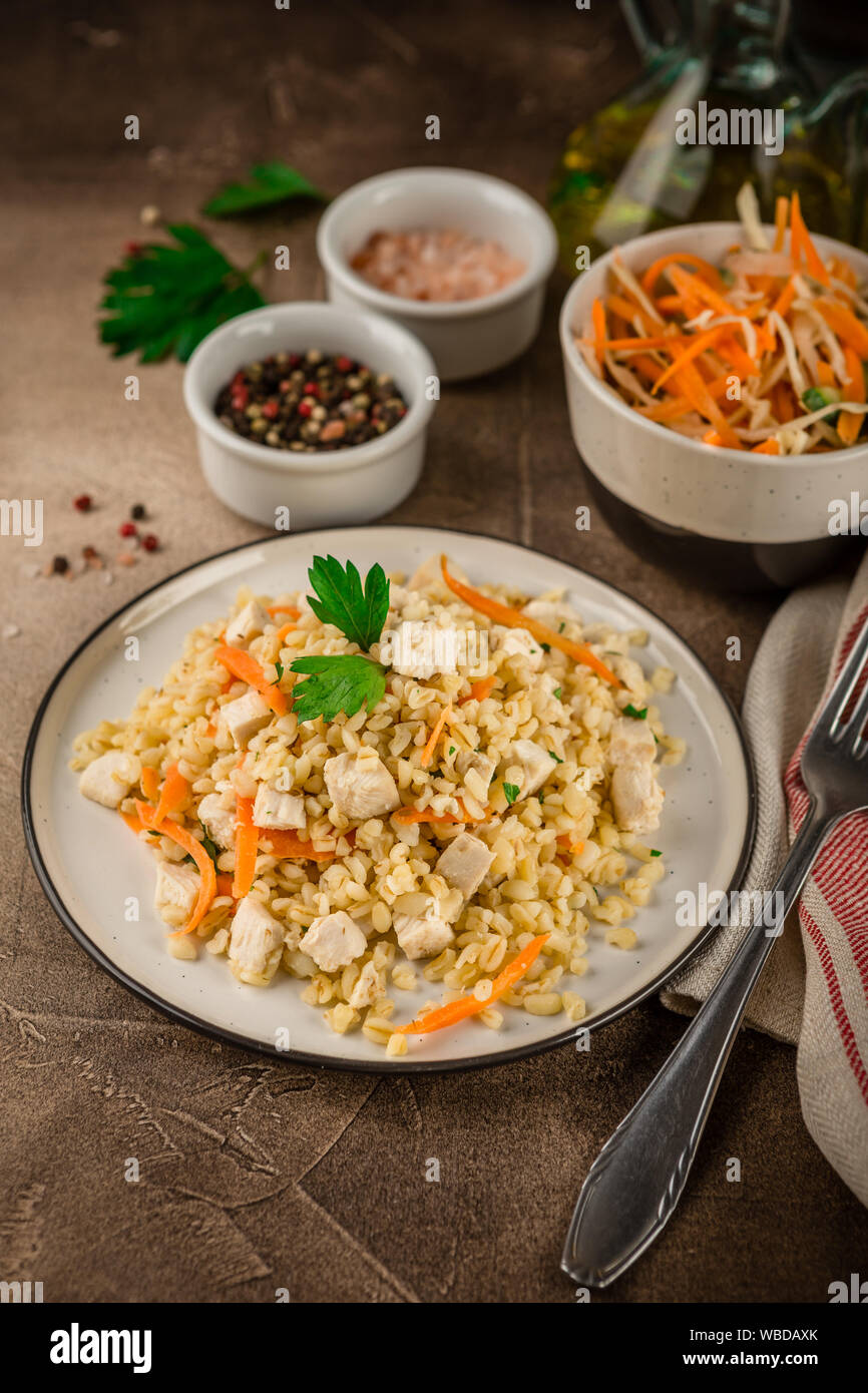 Bulgur Pilaf with chicken in a plate and a bowl of coleslaw on a brown