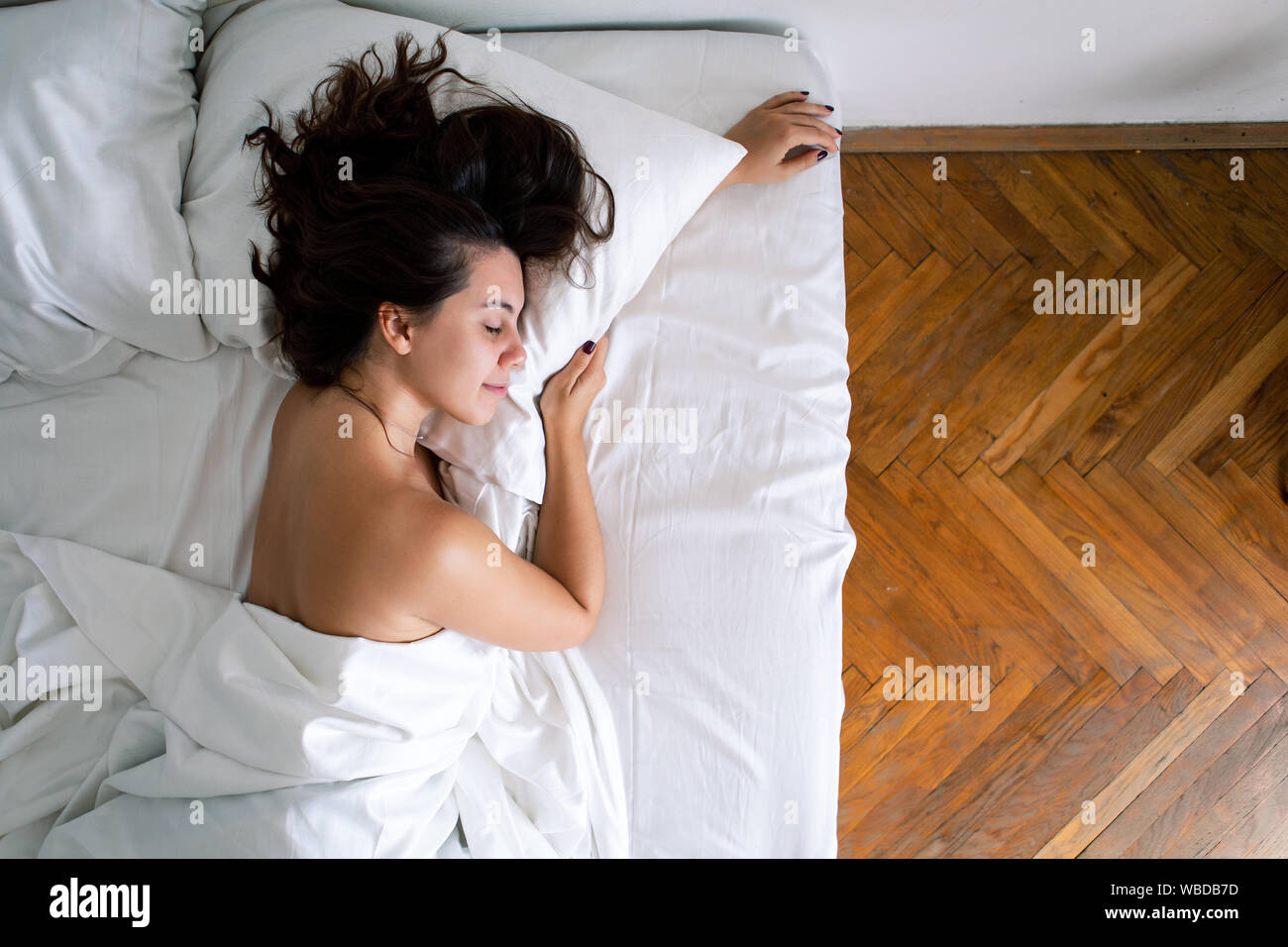 young pretty caucasian woman sleeping in bed with white sheets Stock Photo