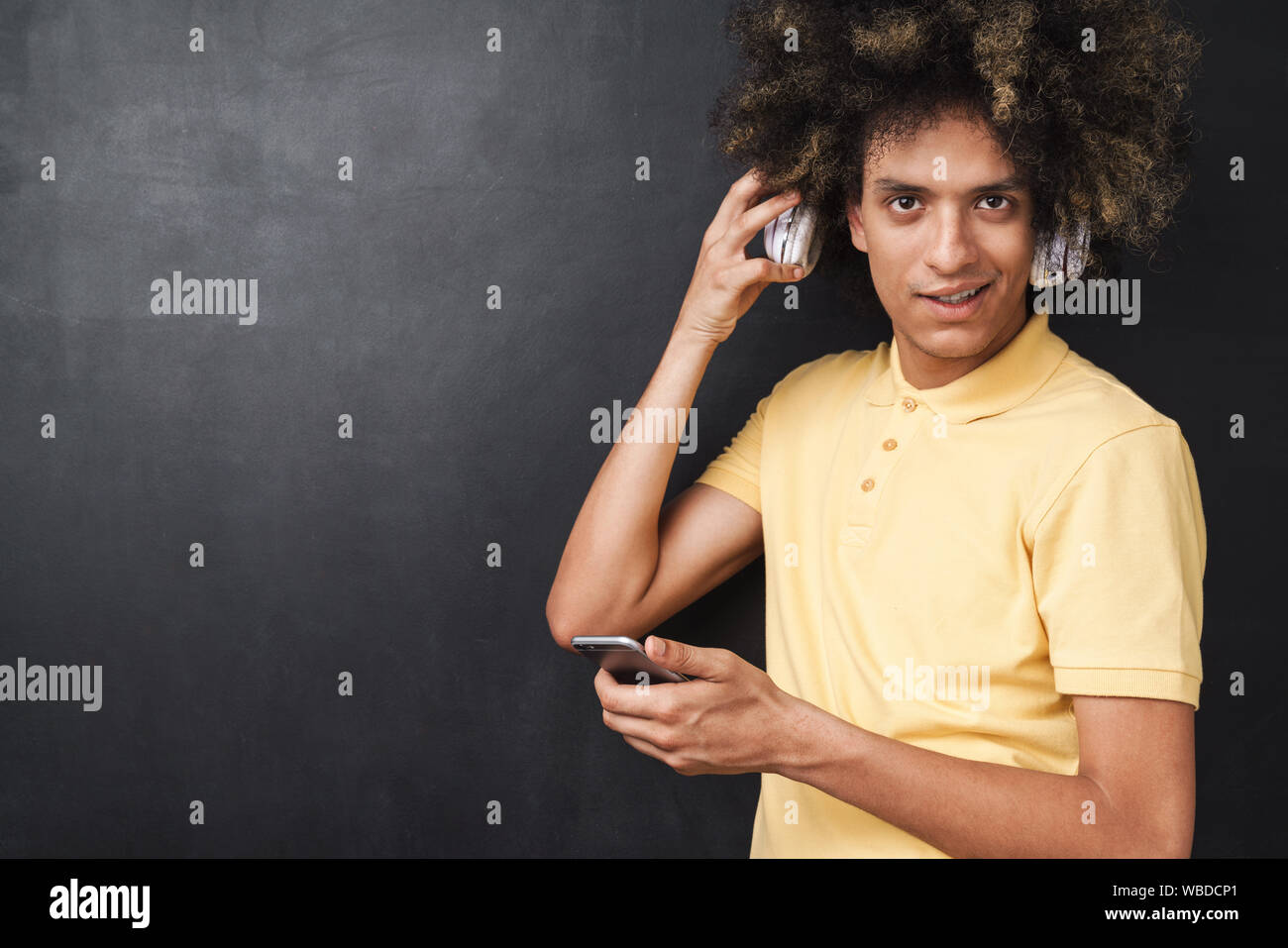 Image Of A Curly Young Teenage Guy Posing Over Grey Chalkboard