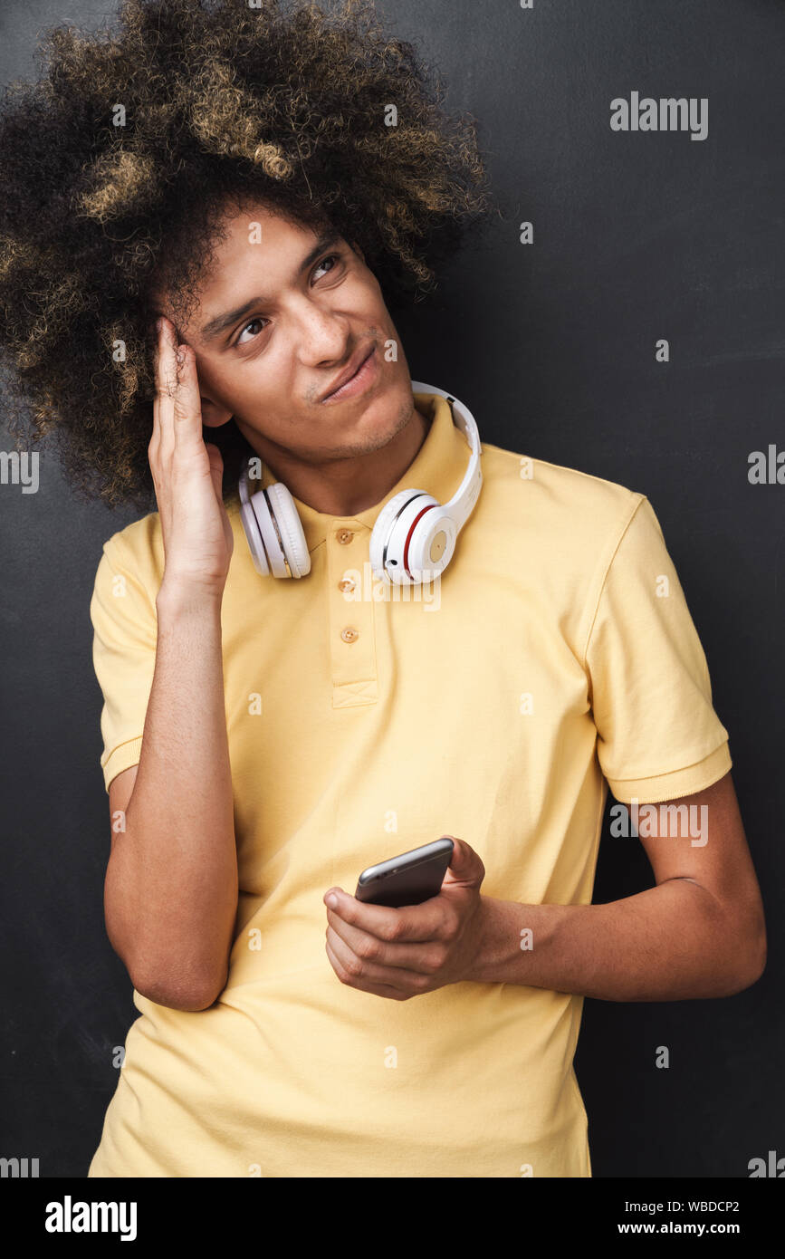 Photo Of A Curly Young Thinking Serious Teenage Guy Posing Over