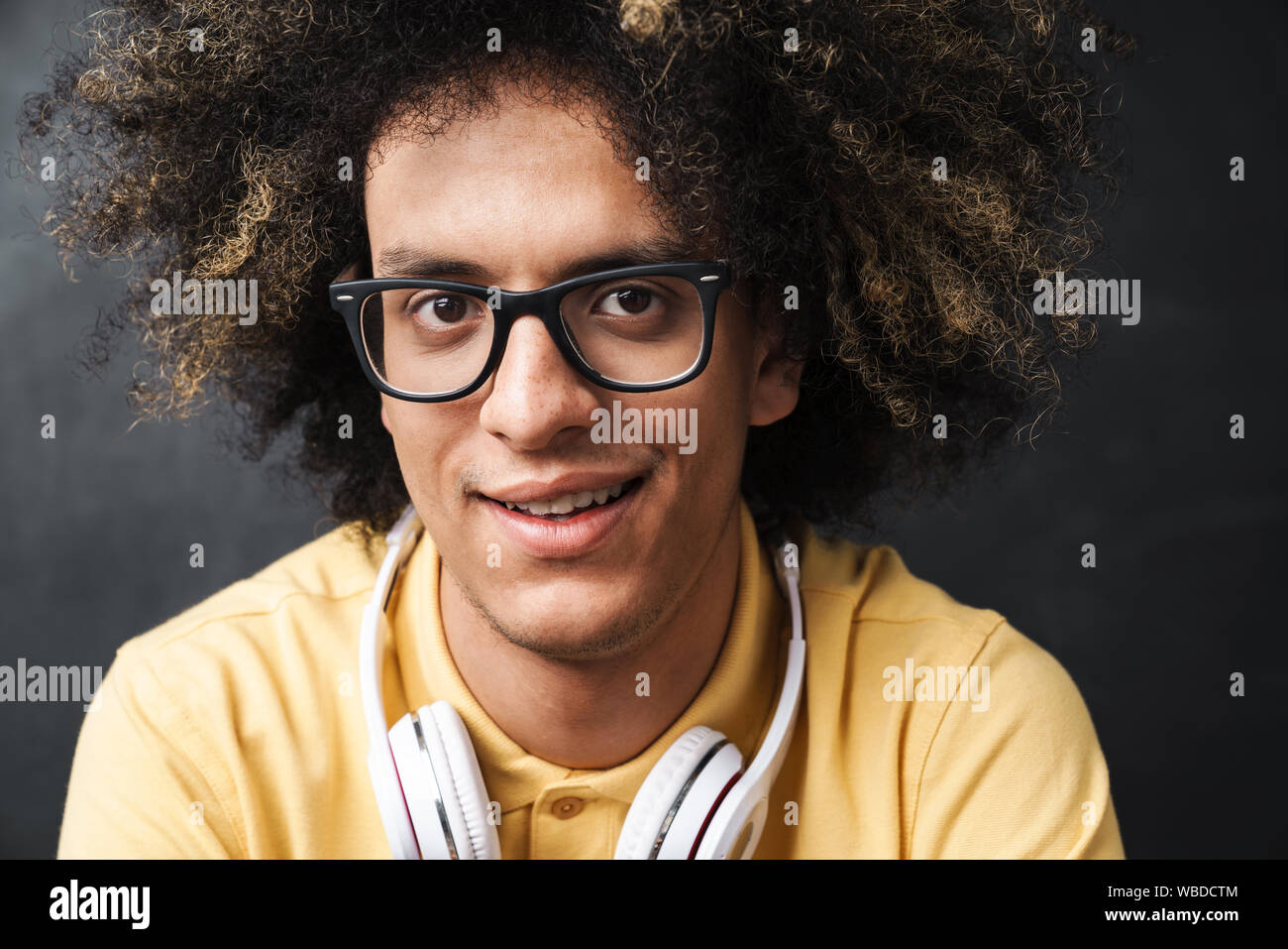 Photo Of A Curly Young Optimistic Smiling Teenage Guy Posing Over