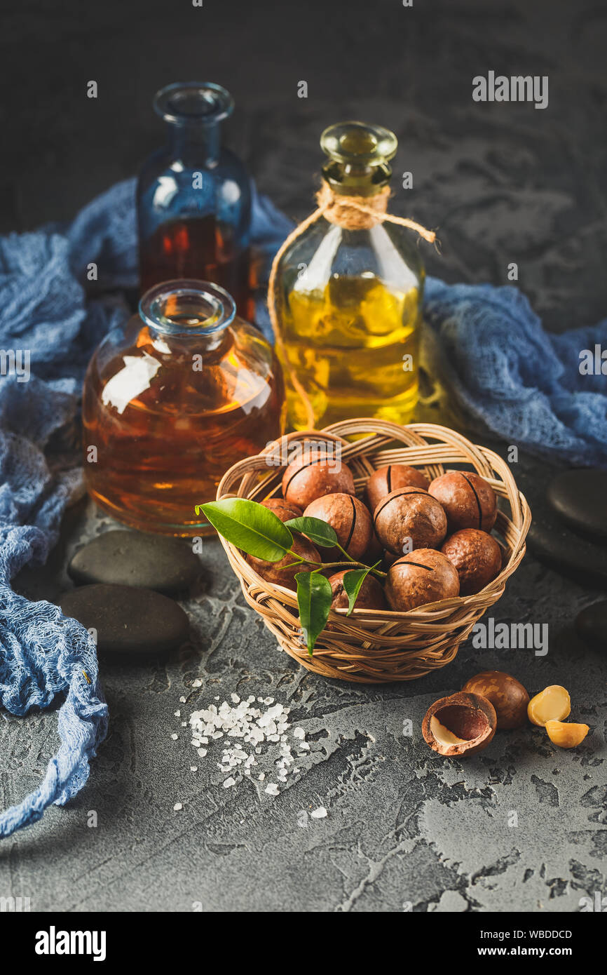 Glass bottles with Natural macadamia oil with macadamia nuts, sea salt and zen stones. Superfood and healthy food concept Stock Photo