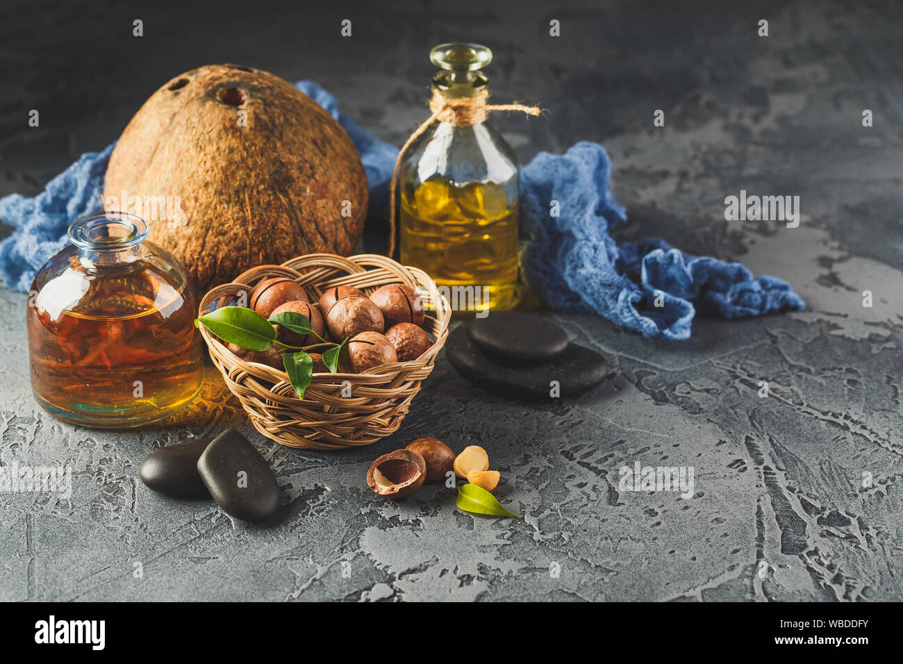 Natural macadamia and coconut oil in a glass bottles with macadamia nuts and cocnut. Use for Healthy Skin and Hair and Natural Healing Oil Treatment Stock Photo