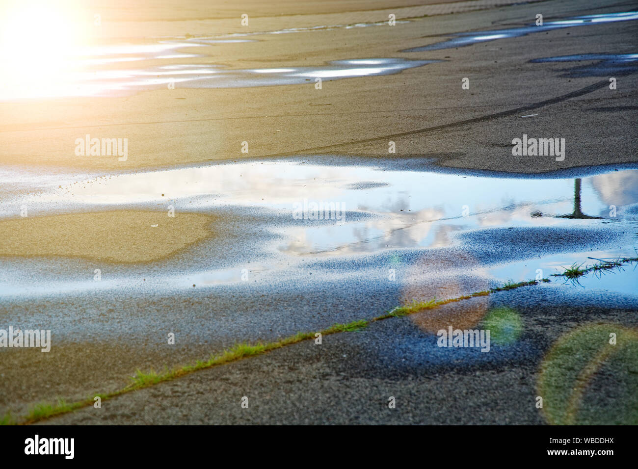 Sky reflected in a puddle of water on pavement, Early morning sunrise ...