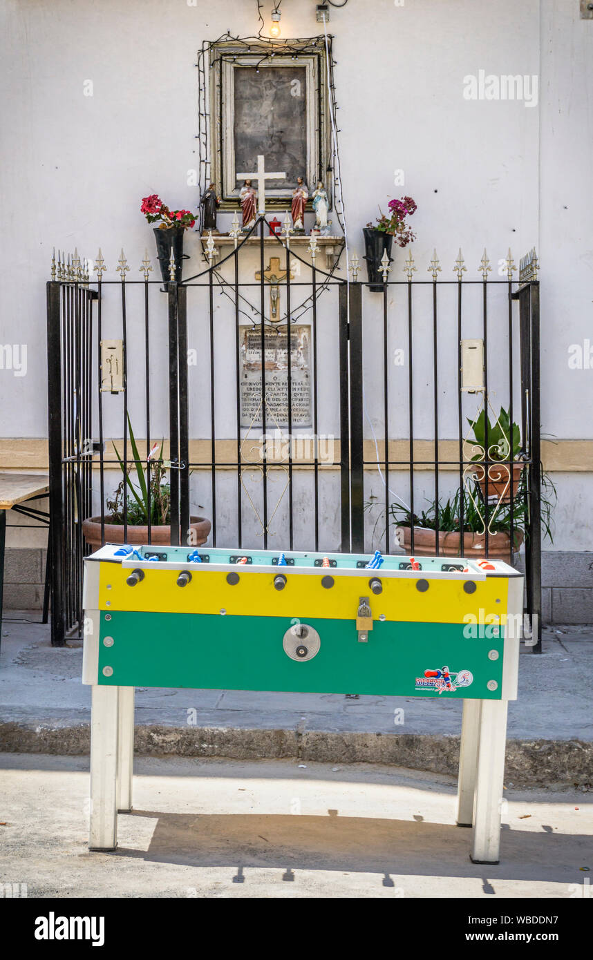 A table football machine stands in front of a street shrine in the Ballaro - Albergheria district of central Palermo, Sicily, Italy. Stock Photo