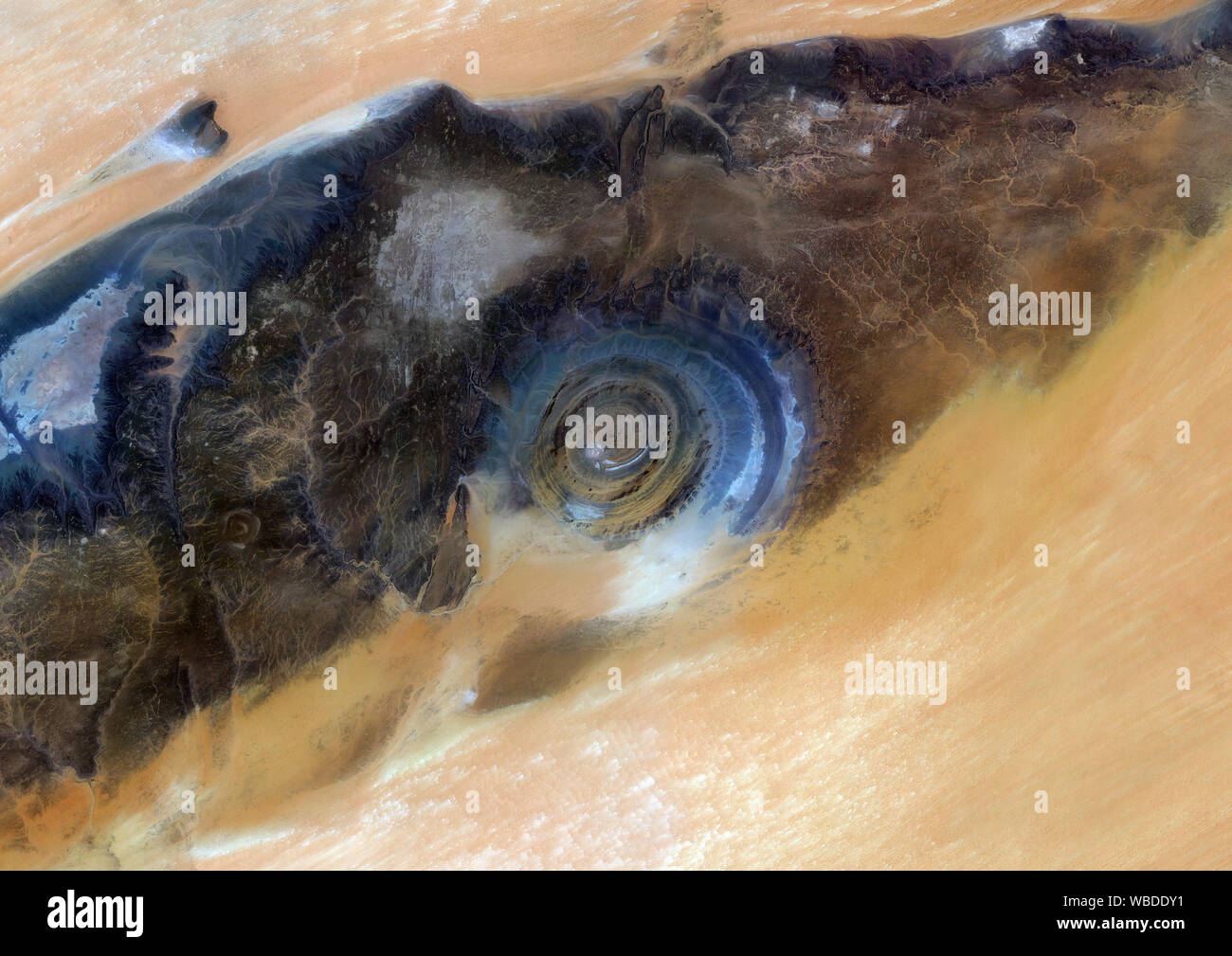 Color satellite image of the Richat Structure, Mauritania. This is a geological formation in the Maur Adrar Desert in the African country of Mauritania. Although it resembles an impact crater, the Richat Structure formed when a volcanic dome hardened and gradually eroded, exposing the onion-like layers of rock. This image was compiled from data acquired by Sentinel-2 & Landsat 8 satellites. Stock Photo