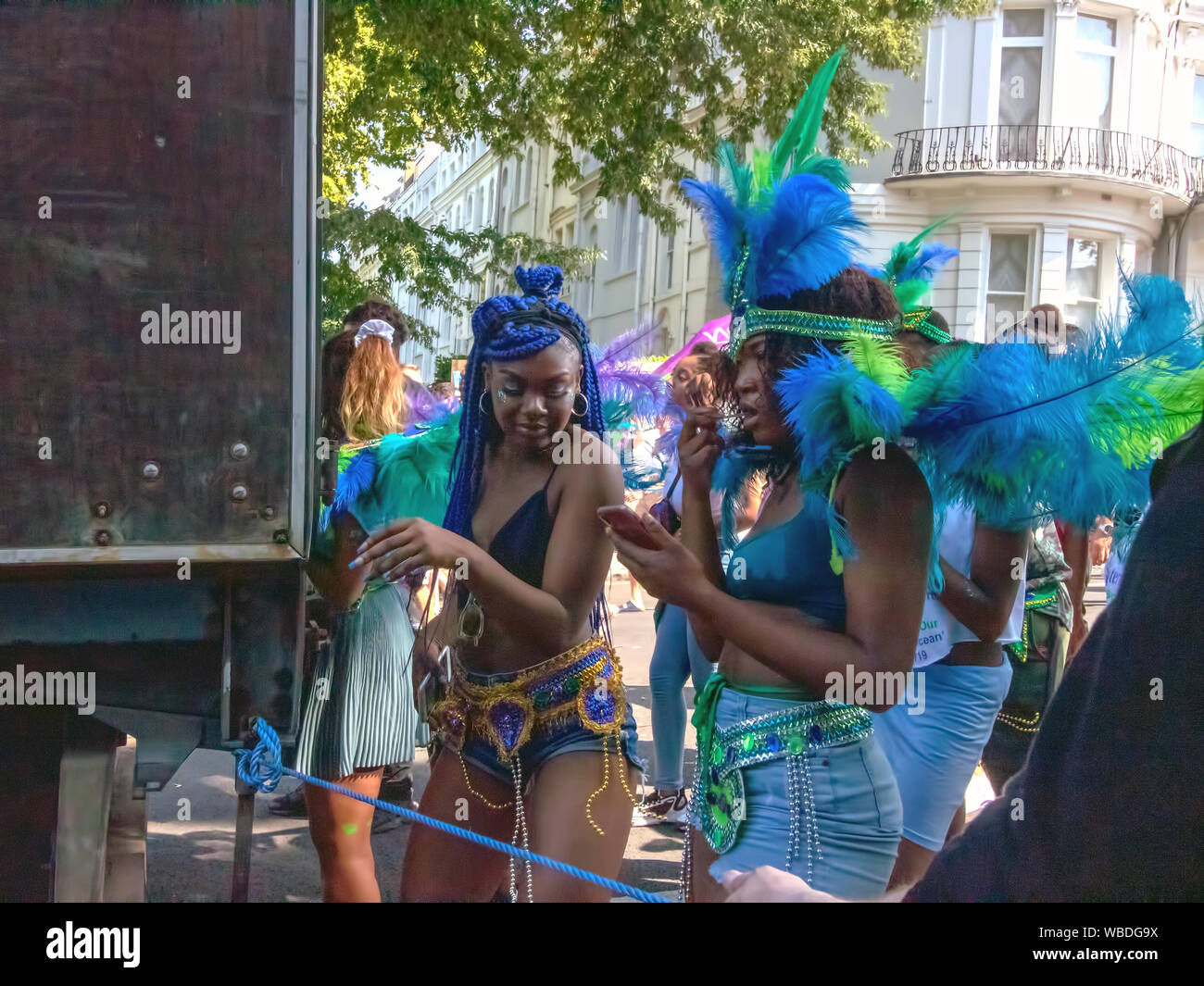 Masqueraders behind a truck during the celebration.The main events of Notting Hill Carnival 2019 got underway, with over a million revellers hitting the streets of West London, amongst floats, masqueraders, steel bands, and sound systems. Stock Photo