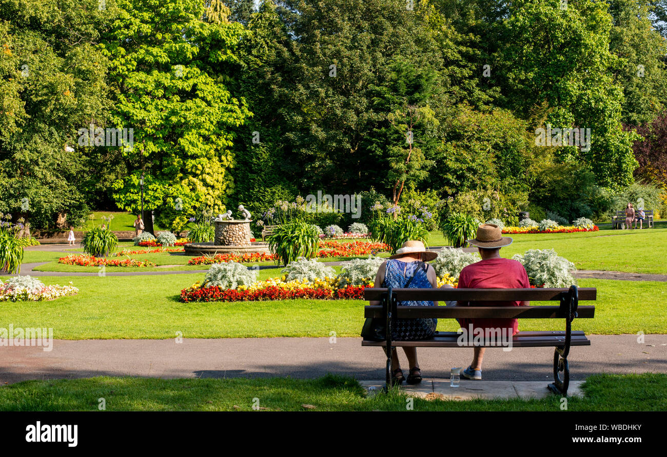 Women resting on park bench on very hot weather, Bank Holiday Monday, Valley Gardens, Harrogate, UK, 26 August 2019 Stock Photo