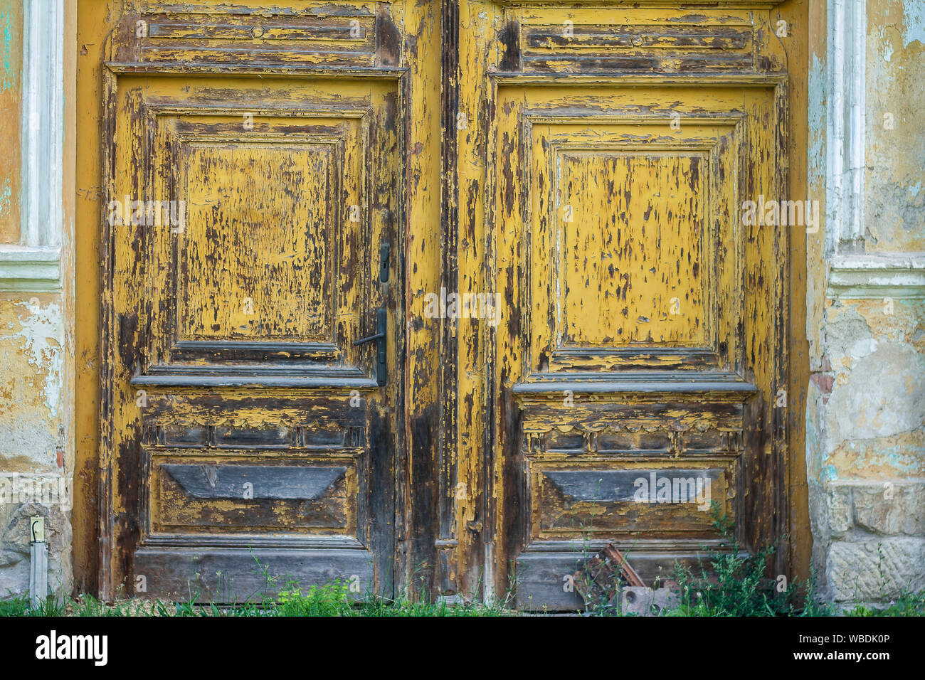 weathered wood door with peeling yellow paint Stock Photo
