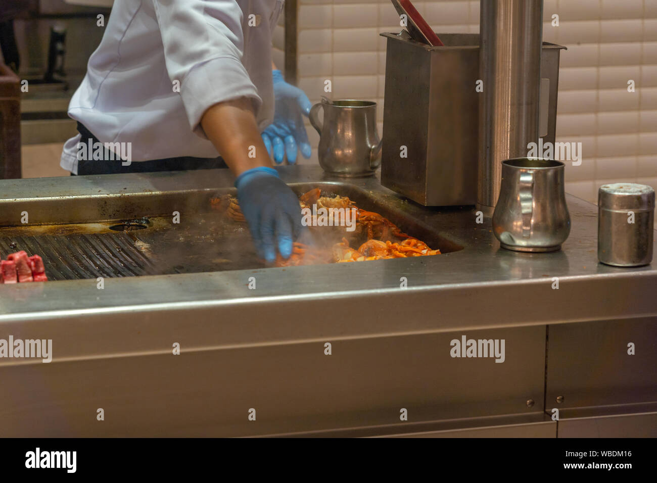 Asian Chef Cooking Grilled Lobster On Electric Stove In Kitchen