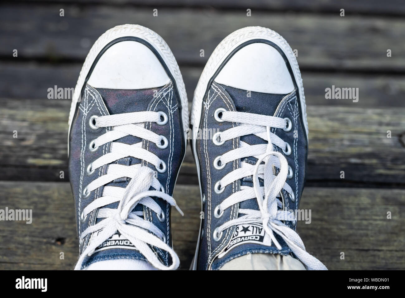 Kouvola, Finland - 18 August 2019: Blue sneakers on the feet on wooden  background. Top view Stock Photo - Alamy