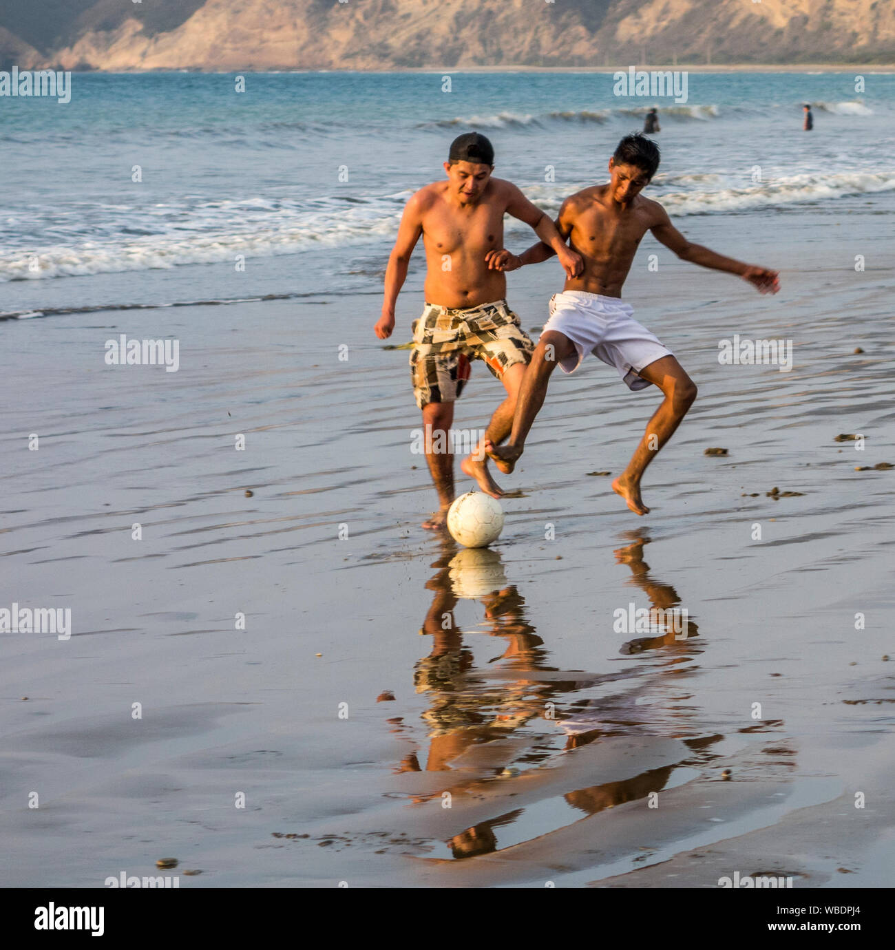 Puerto Lopez, Ecuador - Nov 24, 2012: Two boys play futbol - soccer - on the beach Stock Photo