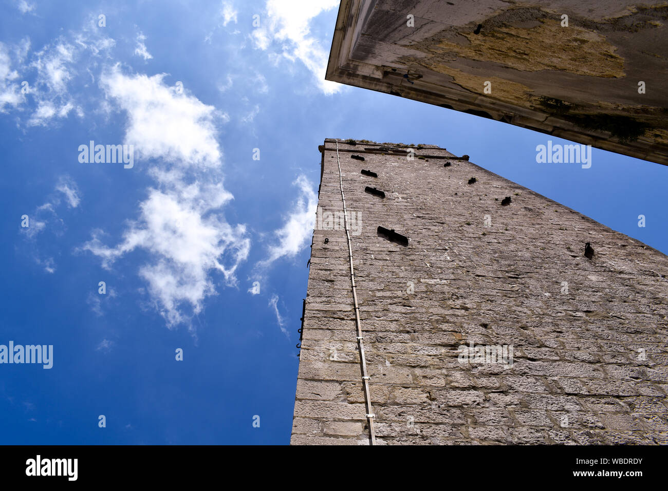 Ground view of roman tower in Motovun, Croatia. Blue sky with right white clouds during summer day. Stock Photo
