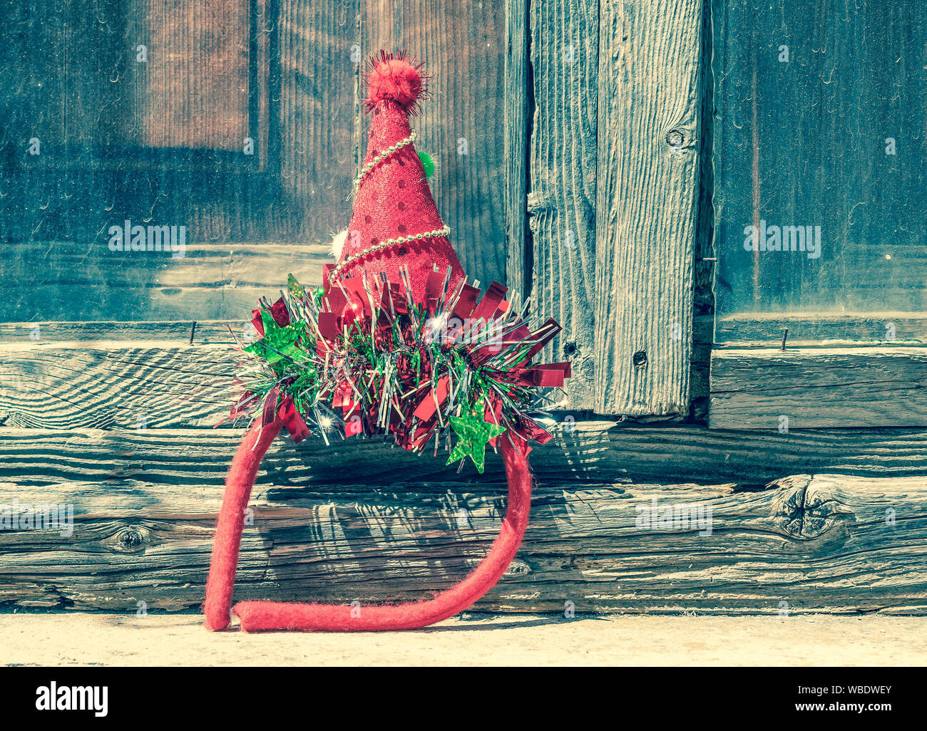 Christmas festive party hat against old wooden door. Red and green shiny celebration diadem. Retro style. Stock Photo