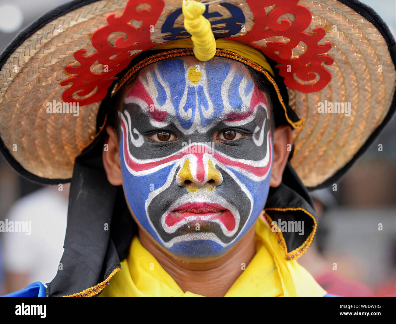 Costumed parade participant with traditional painted face at Bangkok’s colourful Chinese New Year street parade poses for the camera. Stock Photo