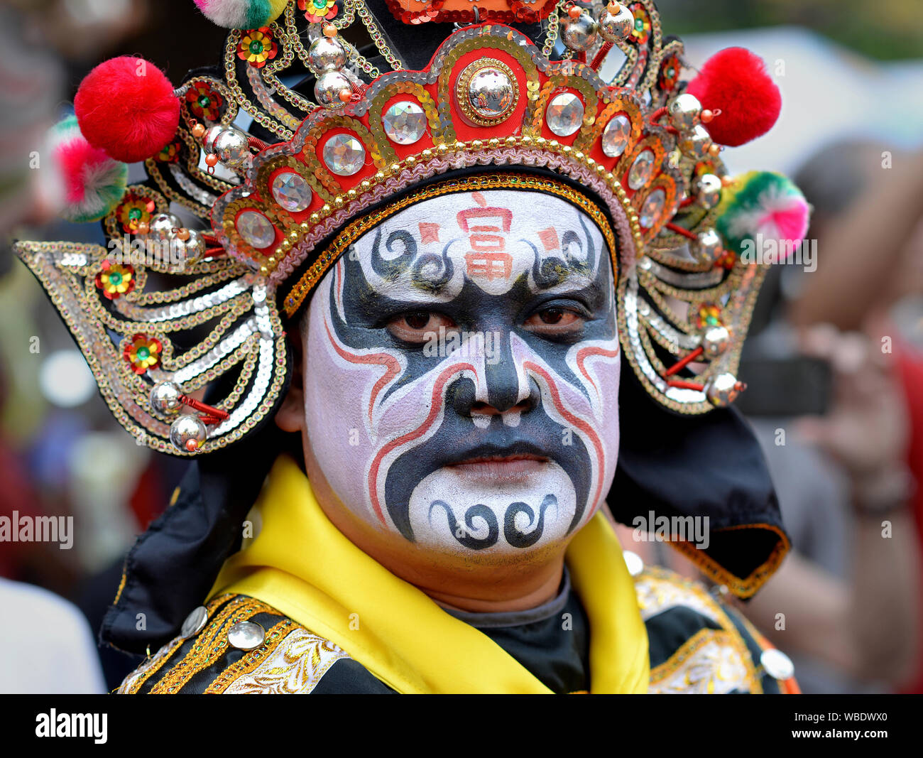 Costumed participant with elaborate traditional headdress and painted face at Bangkok’s Chinese New Year street parade poses for the camera. Stock Photo