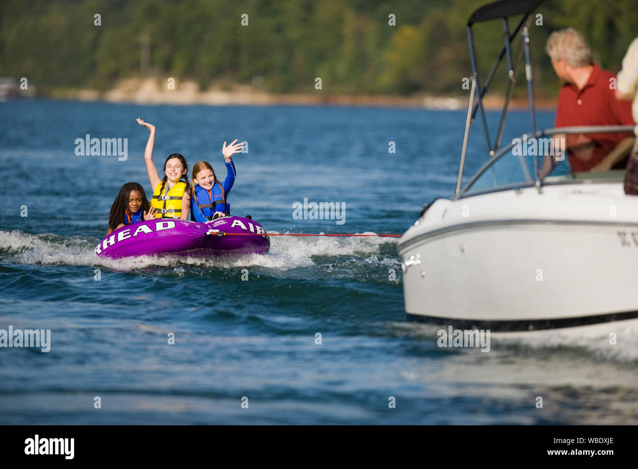Girls riding a biscuit behind a speedboat Stock Photo - Alamy