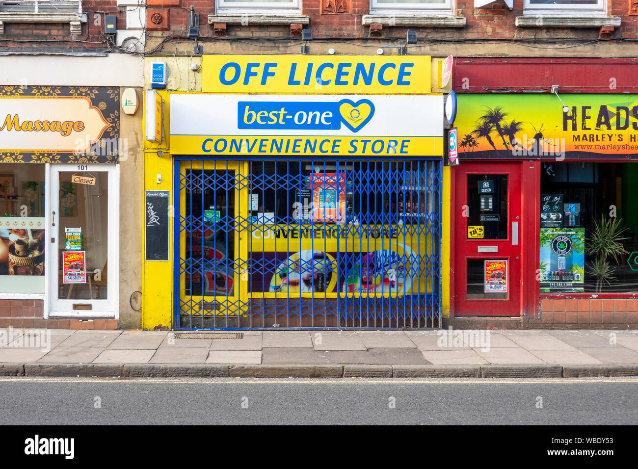 Off licence and convenience store closed and protected by metal barrier Stock Photo