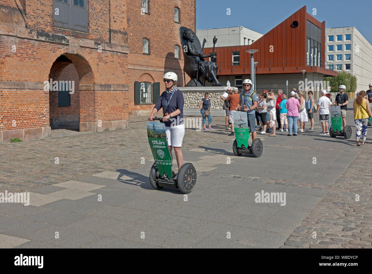 Tourists on guided segway tour passing black sculpture of Mary Thomas in front of the old West Indian Warehouse, now Royal Cast Collection. Copenhagen Stock Photo