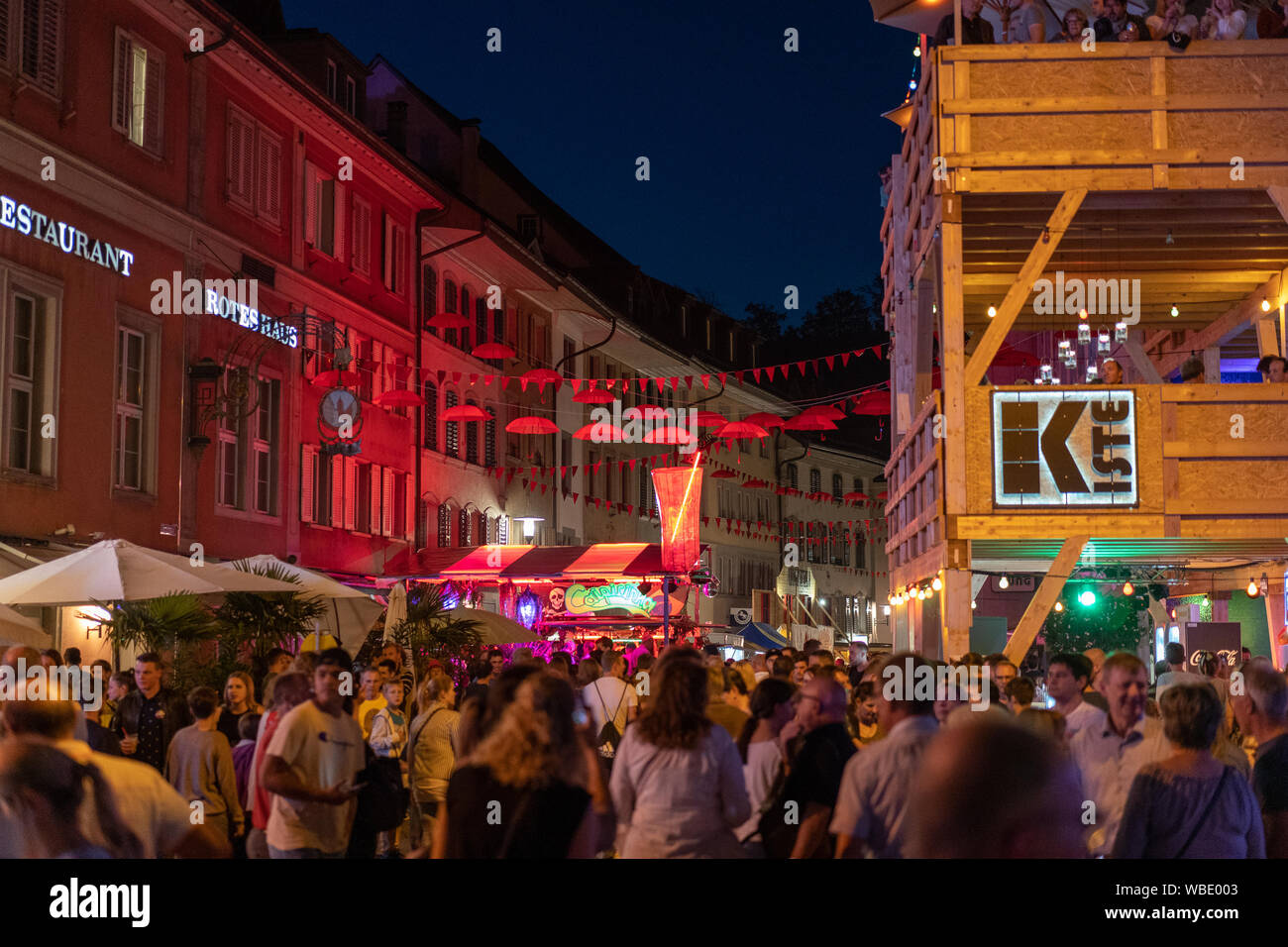 Stadtfest Brugg 24th of august 2019. street photography. illuminated old town of brugg with hanging red umbrellas and red bunting. Stock Photo