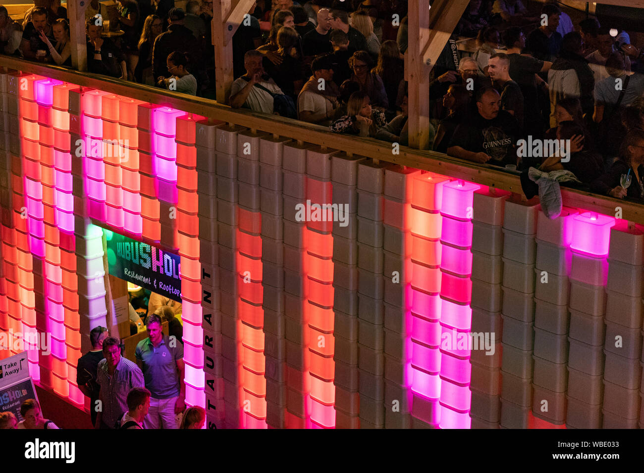 Stadtfest Brugg 24th of august 2019. street photography. Red and pink illuminated plastic wall of Kubus Kolor with people on the top Stock Photo