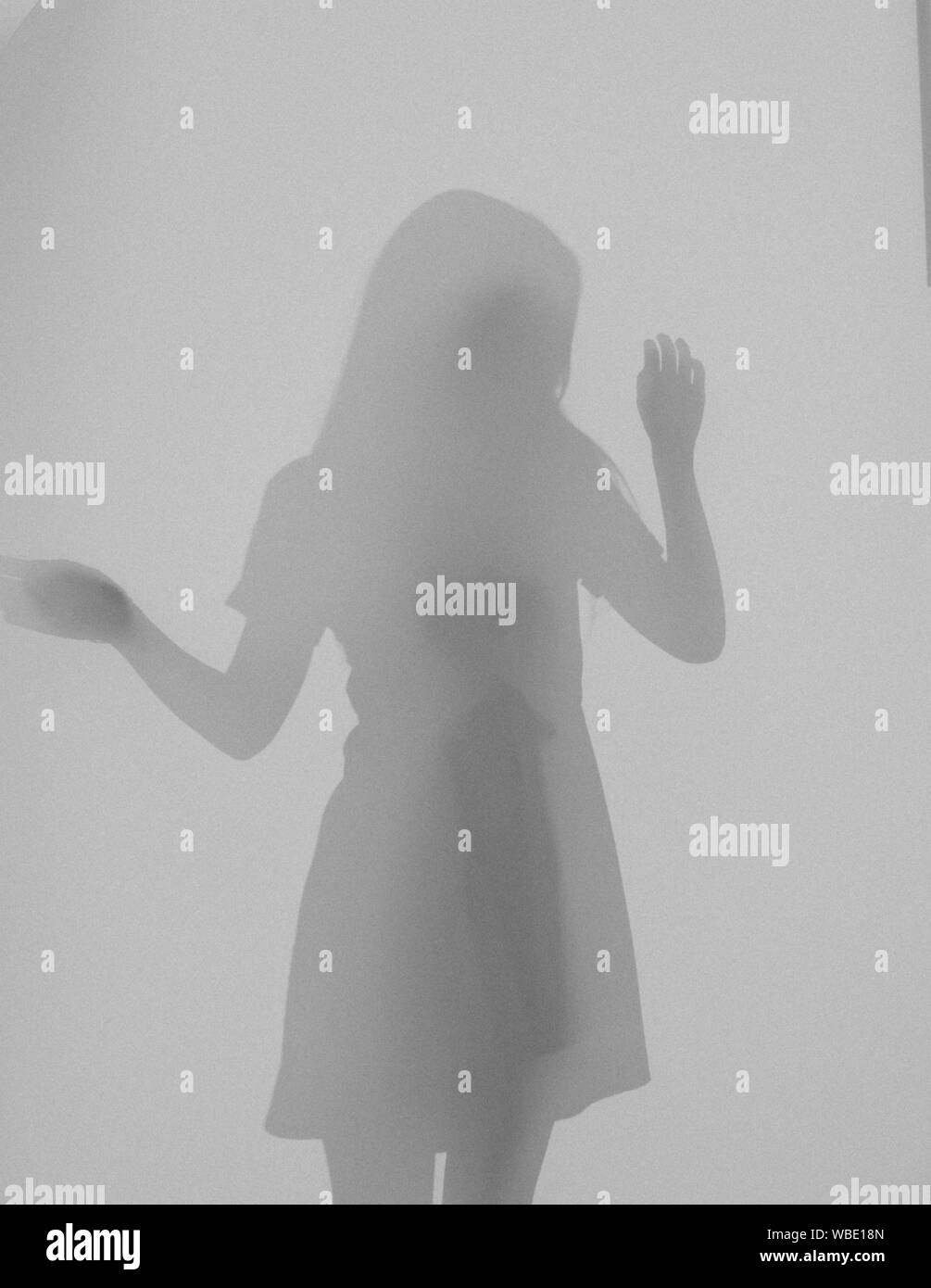 Blurred photo girl wearing dress dancing behind glass Stock Photo