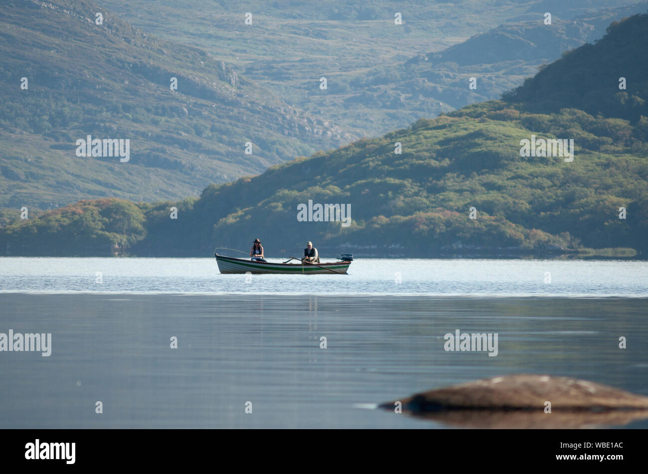 Tranquil view of a carefree couple of fisherman in a row boat fishing in the Lakes of Killarney, Killarney National Park, County Kerry, Ireland. Stock Photo